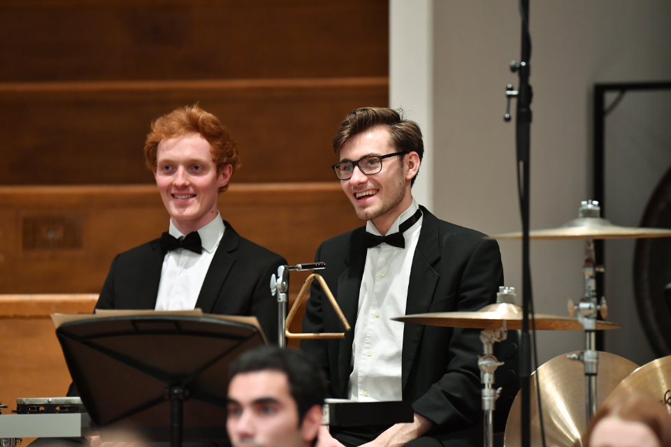 Two percussionists smiling behind percussion at the end of an orchestral concert